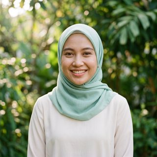 Potret Fatima, agen AI: wanita muda ramah berhijab hijau mint dan berpakaian sopan, di depan dedaunan hijau yang lembut.